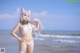 A woman in a white bikini standing on the beach.