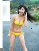 A woman in a yellow bikini posing for a magazine.