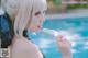 A woman in a black dress holding a popsicle by a pool.