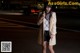 A woman standing in the middle of a street at night.