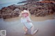 A woman in a white shirt and a straw hat on a beach.