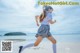 A woman in a school uniform running on the beach.