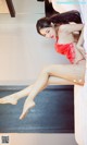 A woman in a red lingerie laying on a bed.