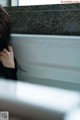 A woman sitting in a bathtub with her head in her hands.