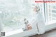 A woman sitting on a window sill holding a stuffed animal.