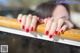 A woman with a red manicure leaning on a railing.