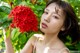 A woman holding a red flower in front of her face.